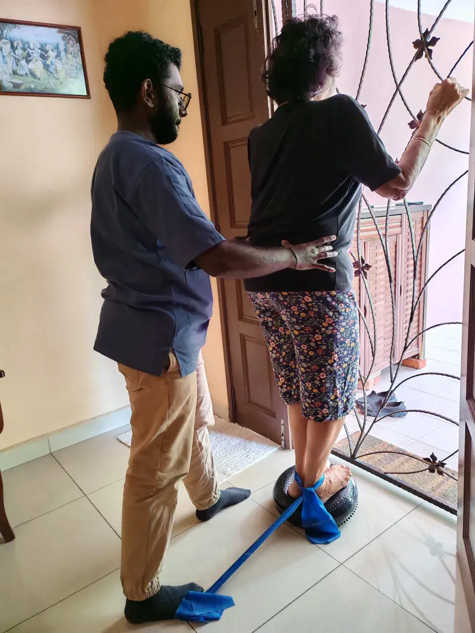 Physiotherapist guiding a patient through balance rehabilitation during a home visit